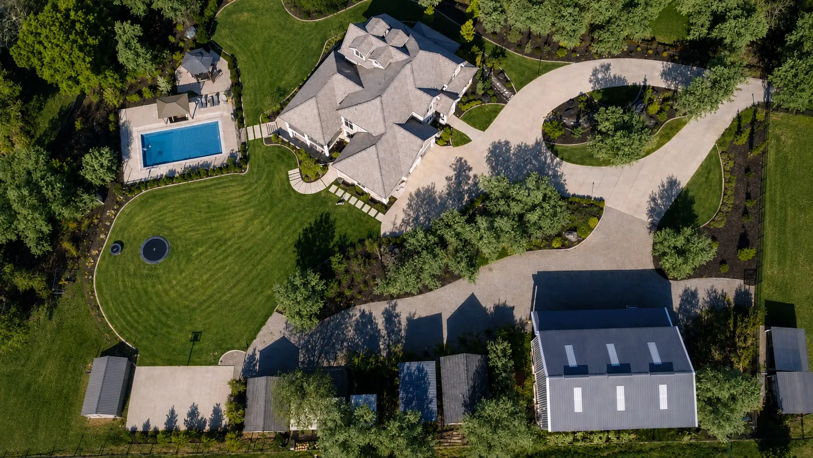 Aerial view of the landscaped grounds, pool, and drive