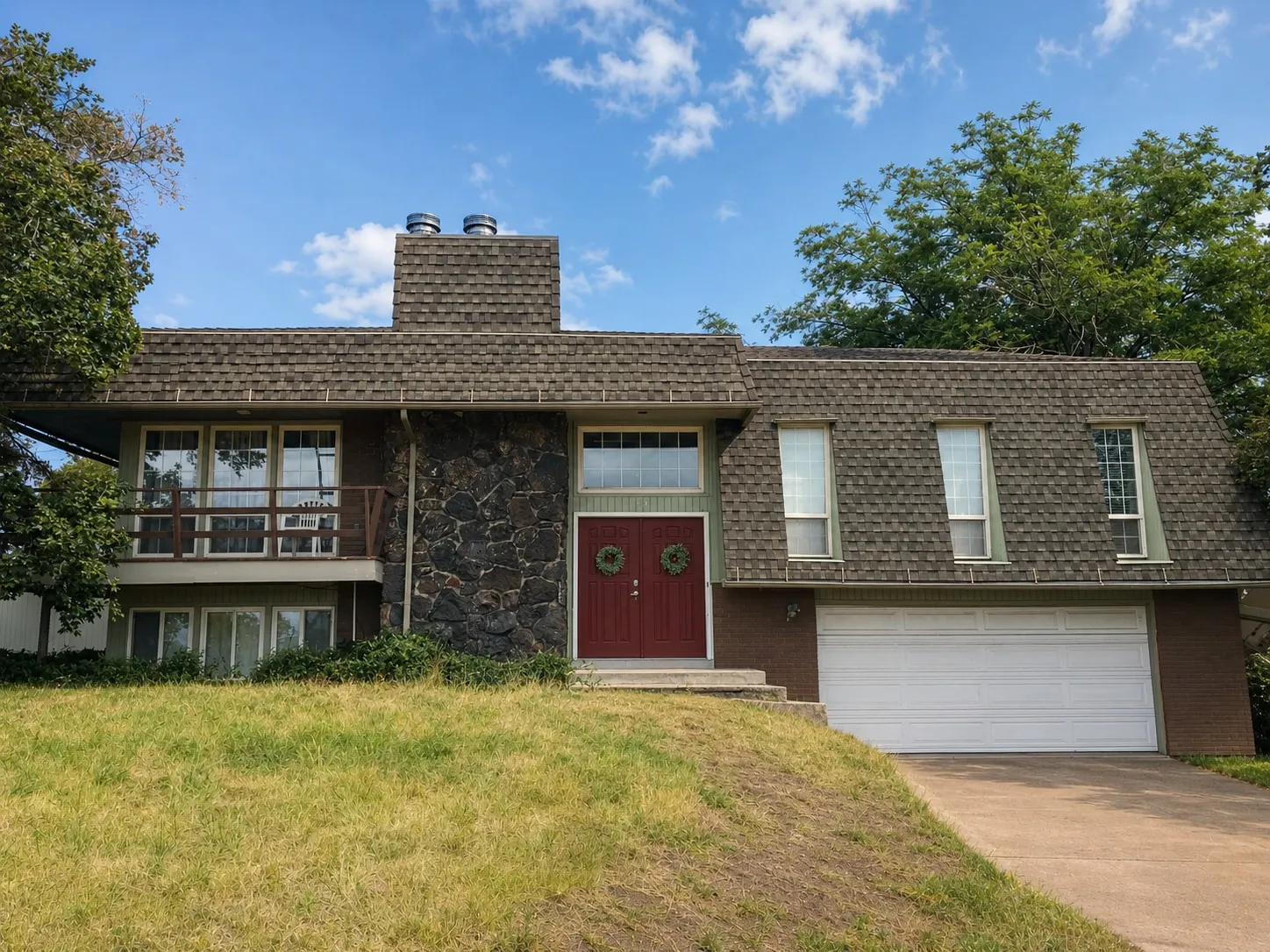 The original 1970s brick-and-shake ranch from the street, with a red front door and low roofline