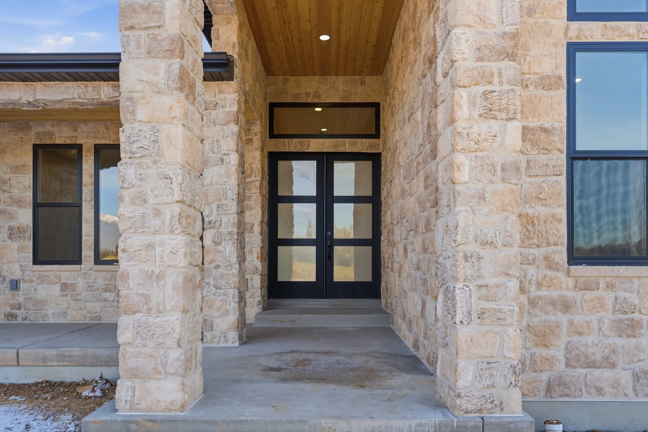 A HydeCo custom home entry framed in full-height natural stone