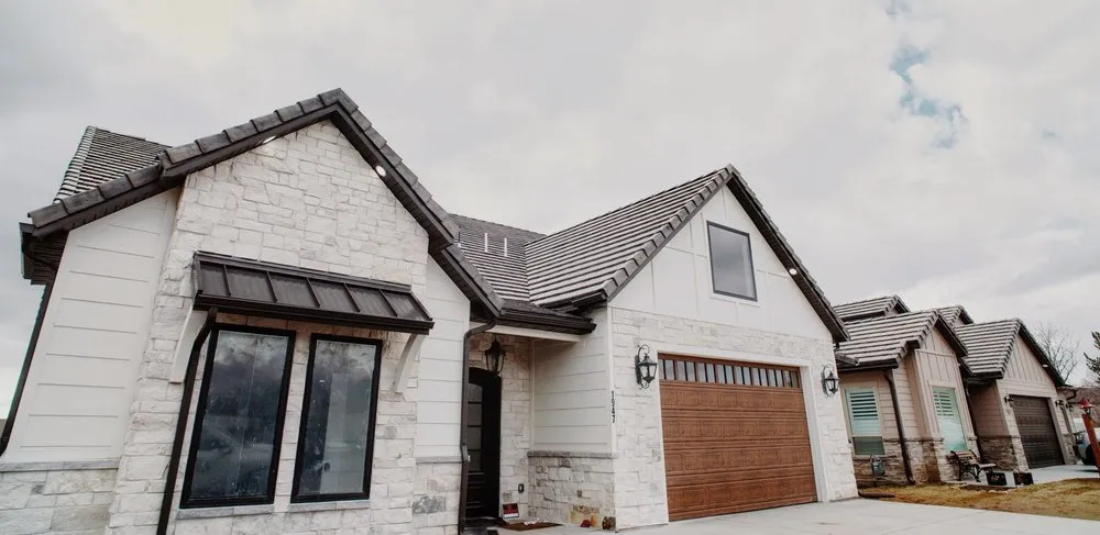 Home exterior detail with stone, cream board-and-batten, and a wood garage door