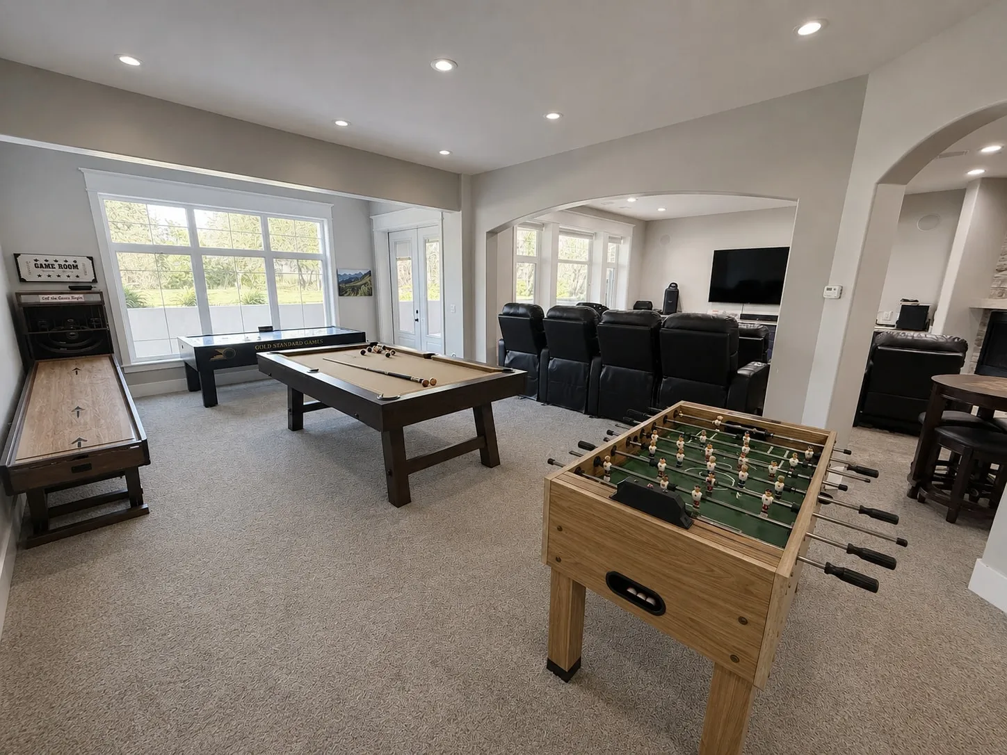 Lower-level game room with pool table, shuffleboard, and foosball